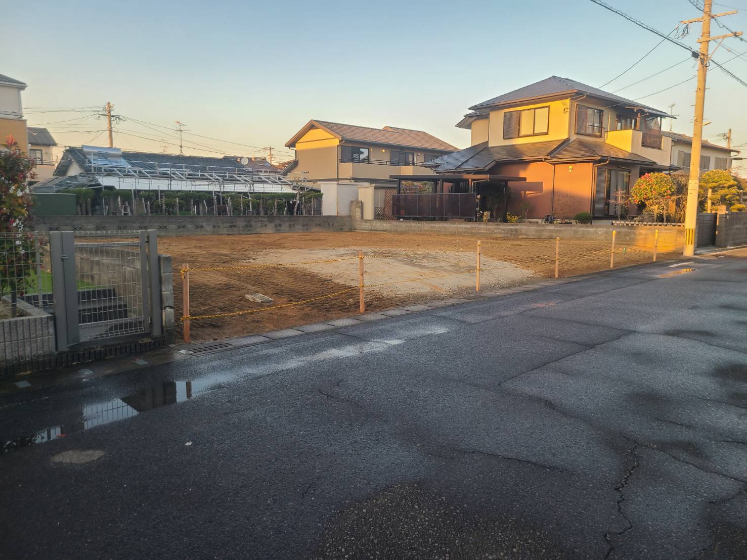 夕日に照らされた解体後の更地と、境界に張った縄（佐賀県佐賀市の施工事例）