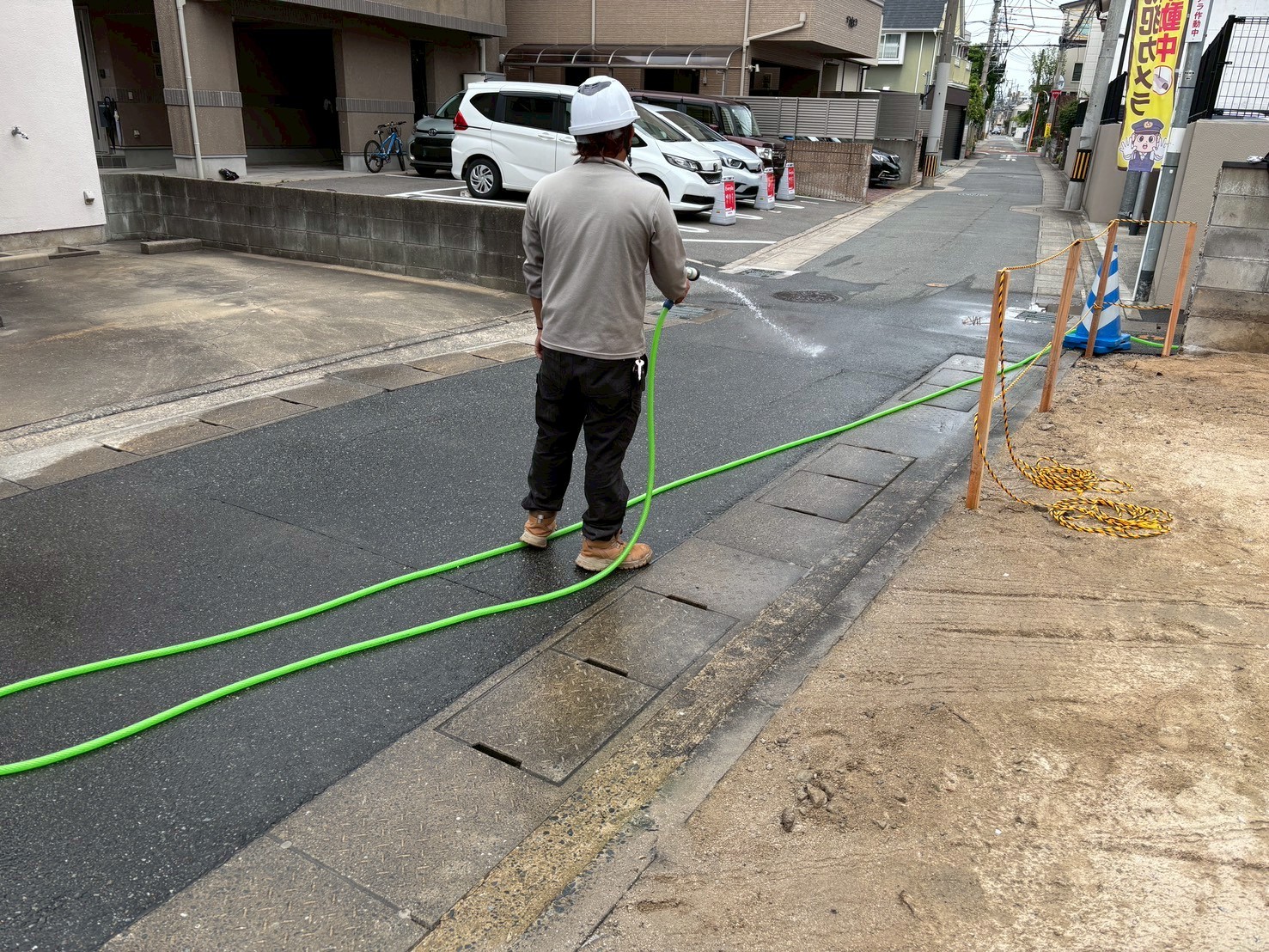 工事の仕上げに現場まわりの道路を水で清掃するサンミライ開発のスタッフ