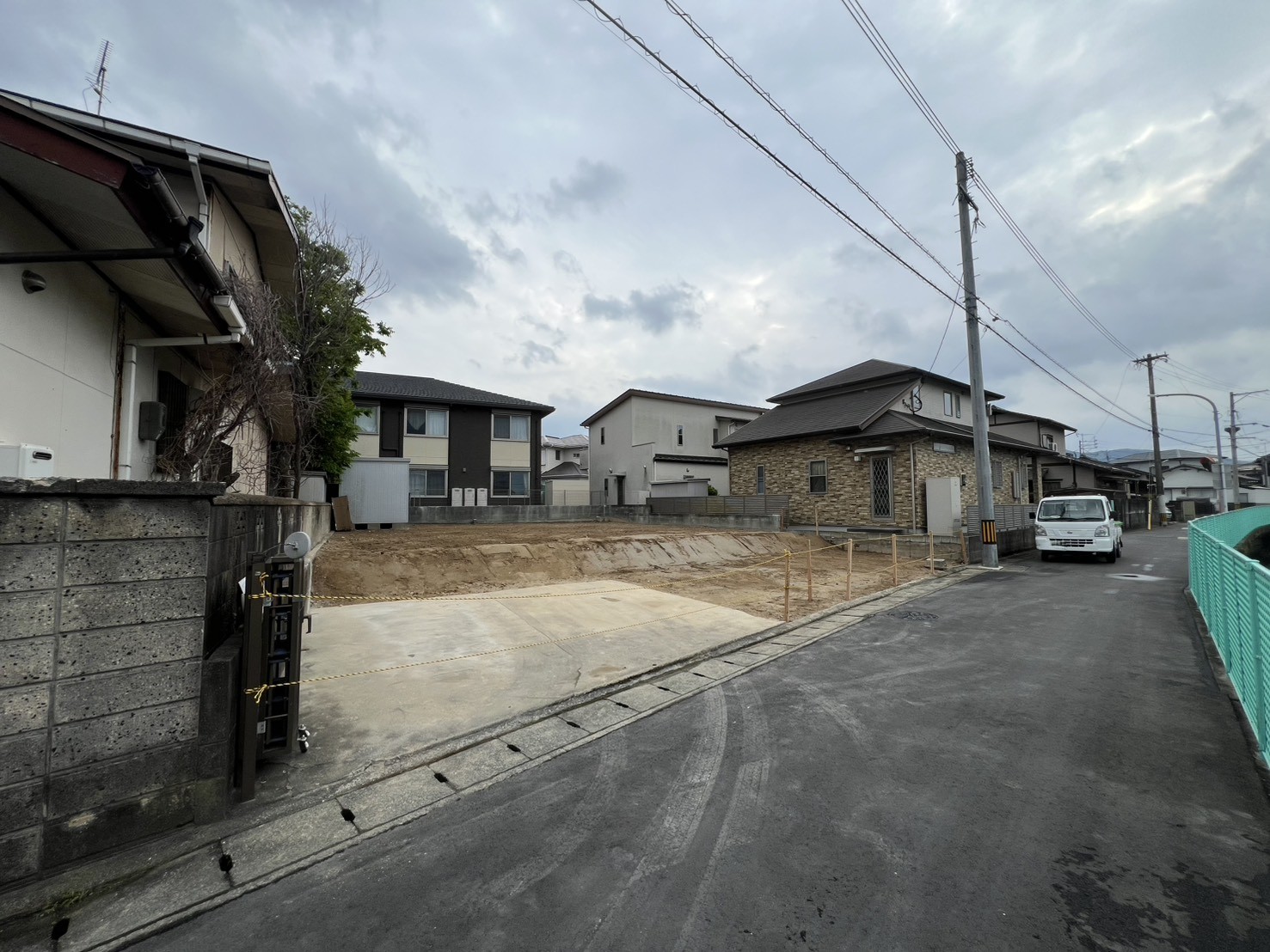 老司 解体工事完工後の様子 道路側からの構図(整地された更地と周囲の住宅街)