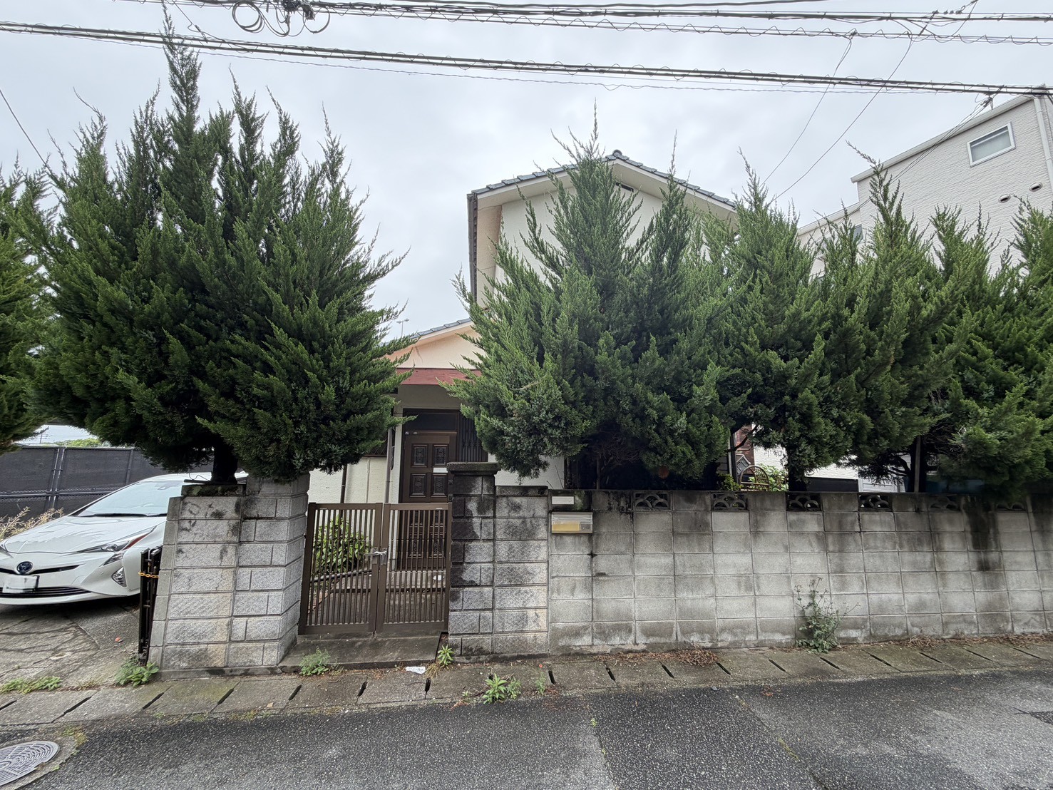 福岡市城南区梅林5丁目の解体工事現場・玄関側からの建物の佇まいとカイヅカイブキの生垣