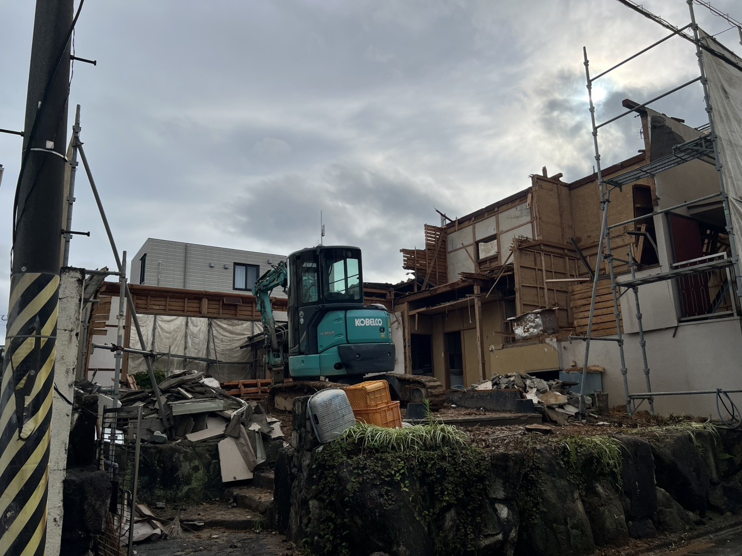 屋根と2階の外壁が外れ、在来工法の木造軸組があらわになった解体中の住宅