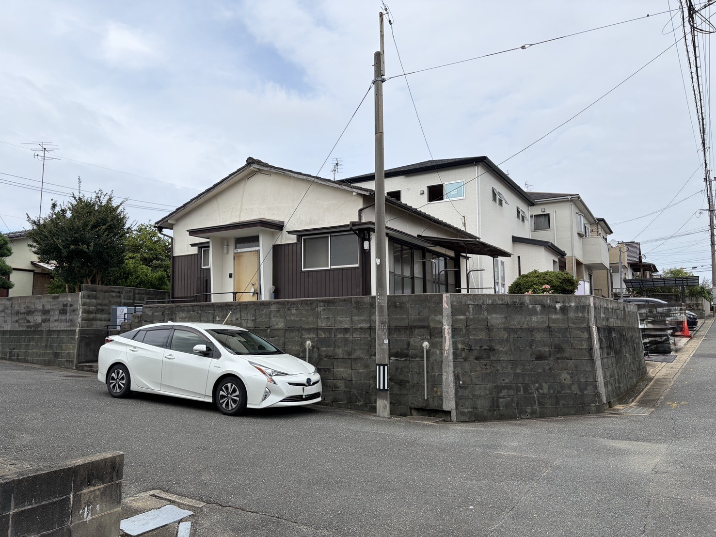 角地から見た木造平屋の全景。石積みの擁壁の上に建つお住まい。福岡市早良区・有田