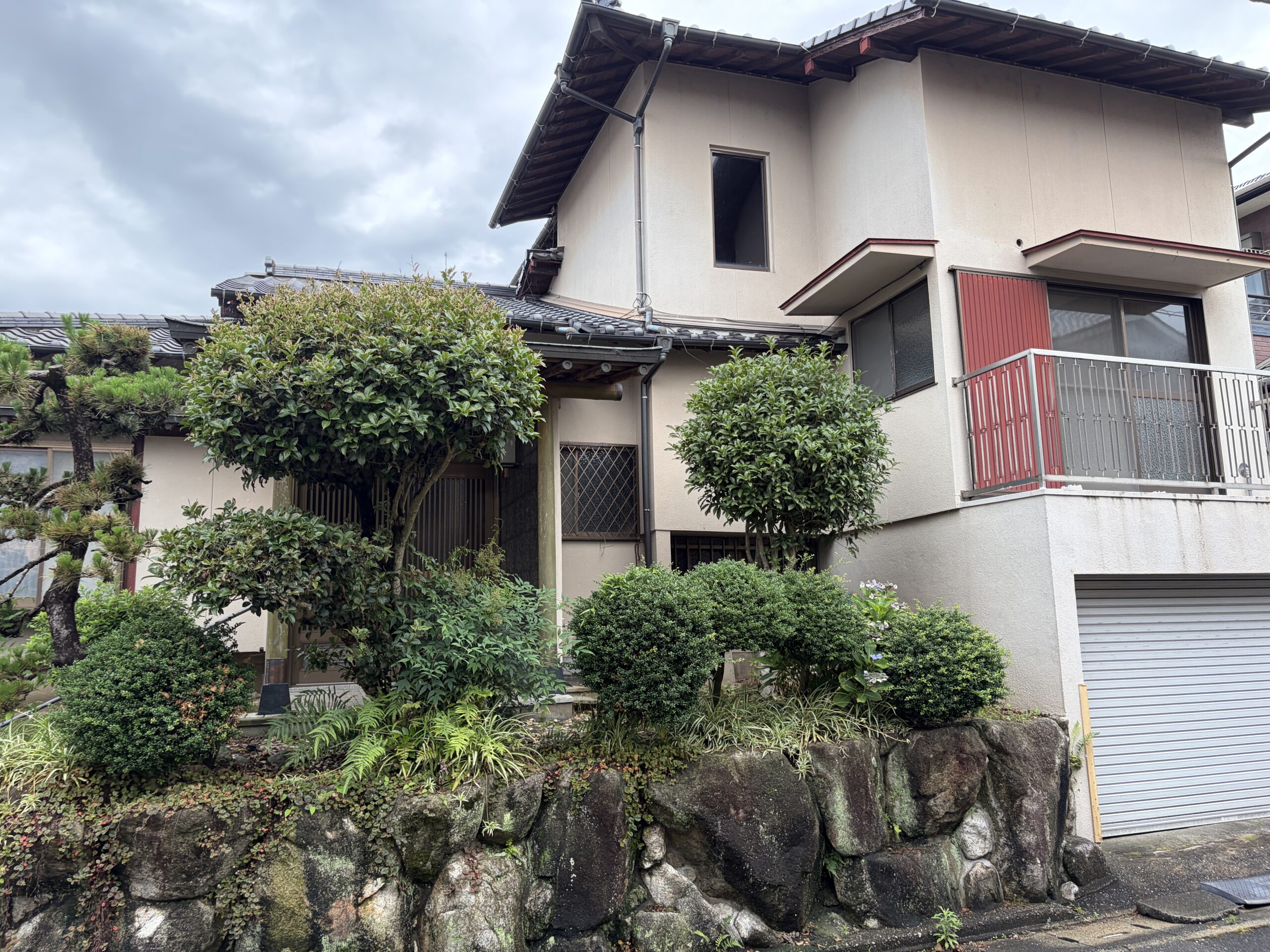 正面から見た、庭木と自然石の石垣が印象的なお住まいの外観