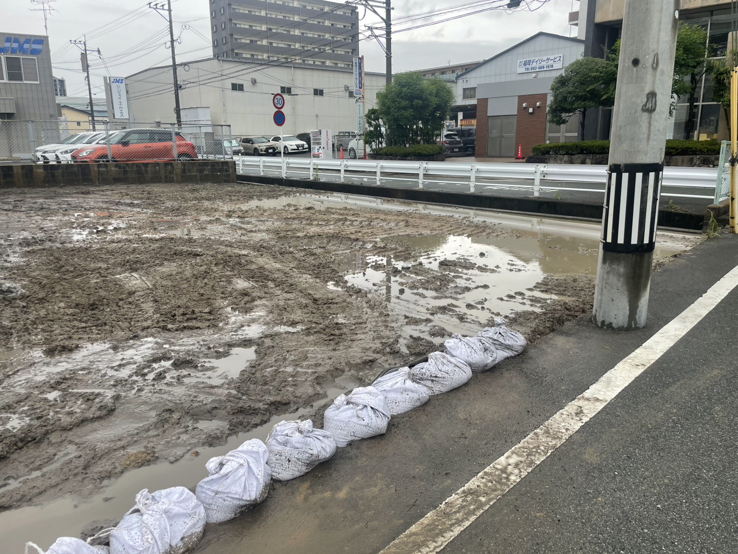 土のうで養生された更地と周囲の様子