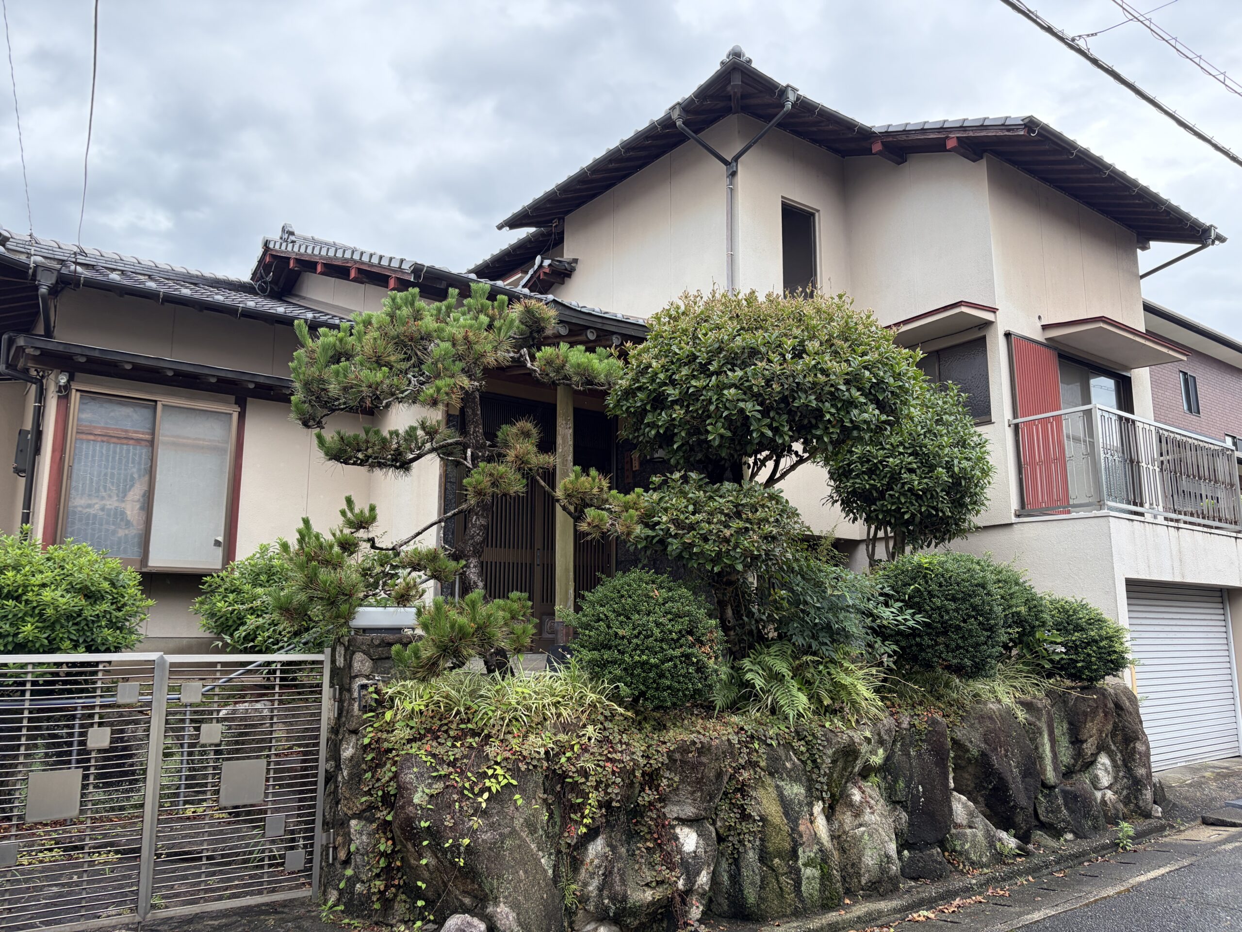 外階段を上がった先の玄関と、枝ぶりの立派な黒松