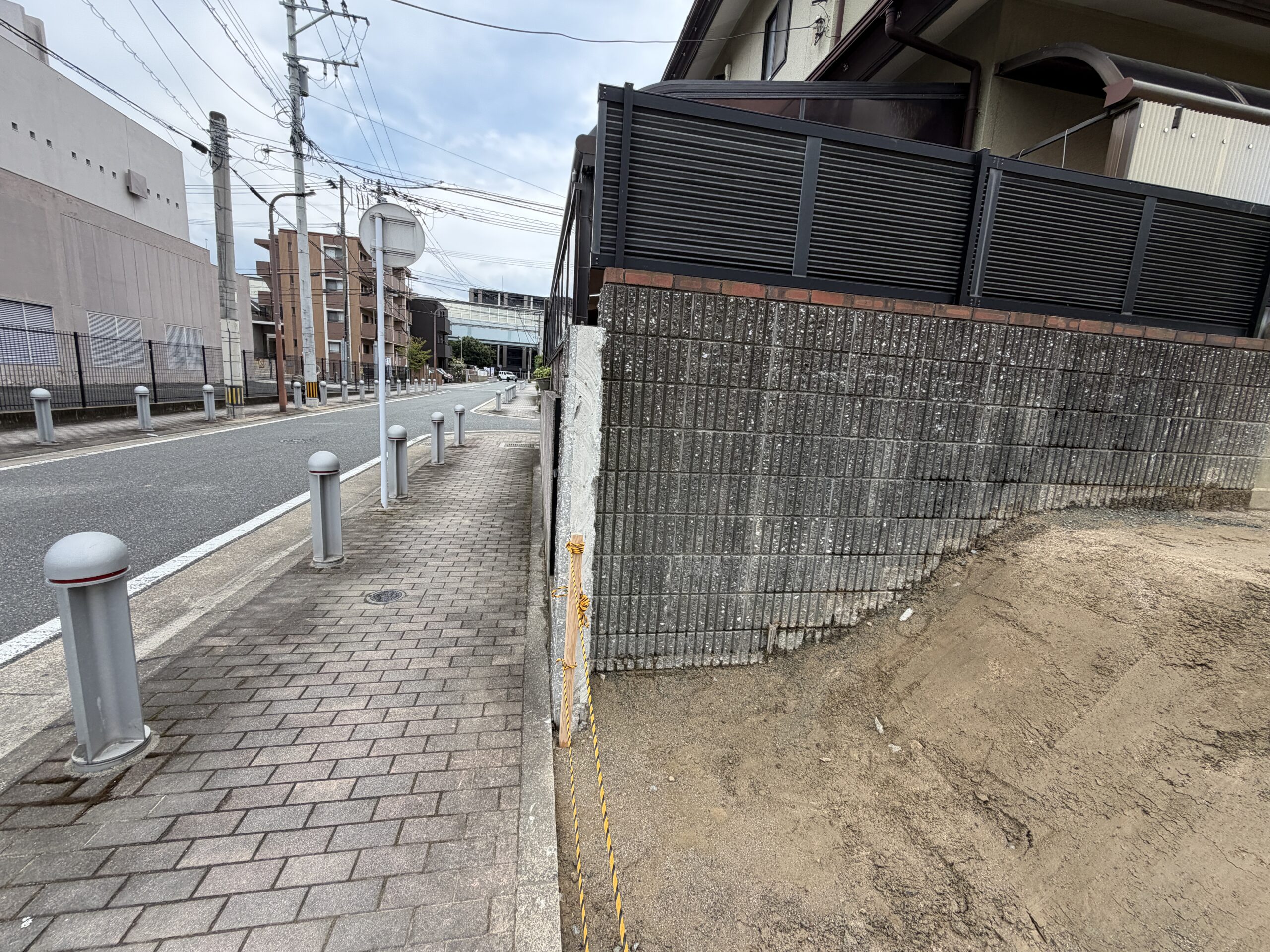 歩道や車止めポールと、生活道路に面した敷地の様子