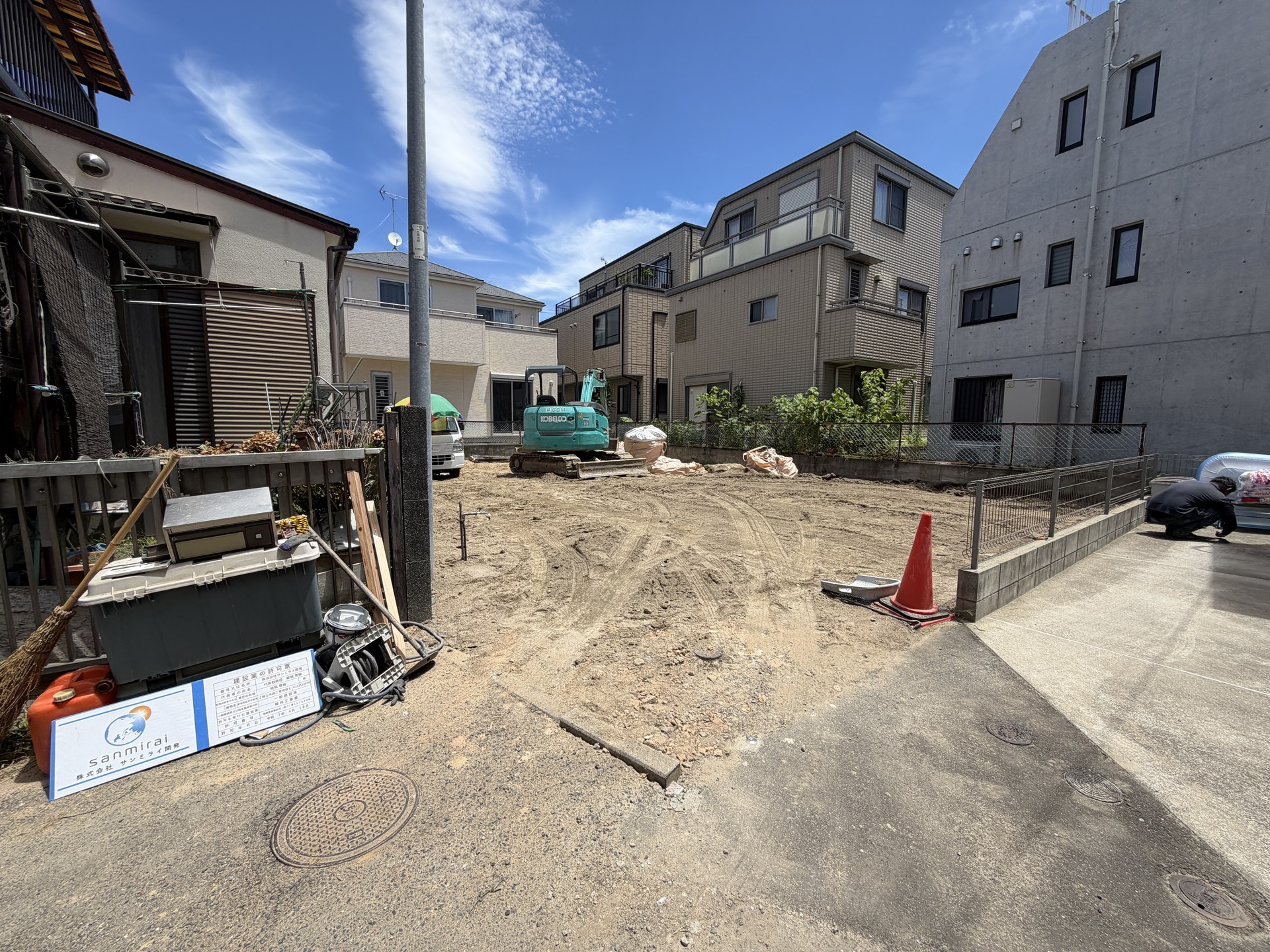 解体を終えた敷地で整地作業を行う小型重機。周囲には住宅が建ち並ぶ