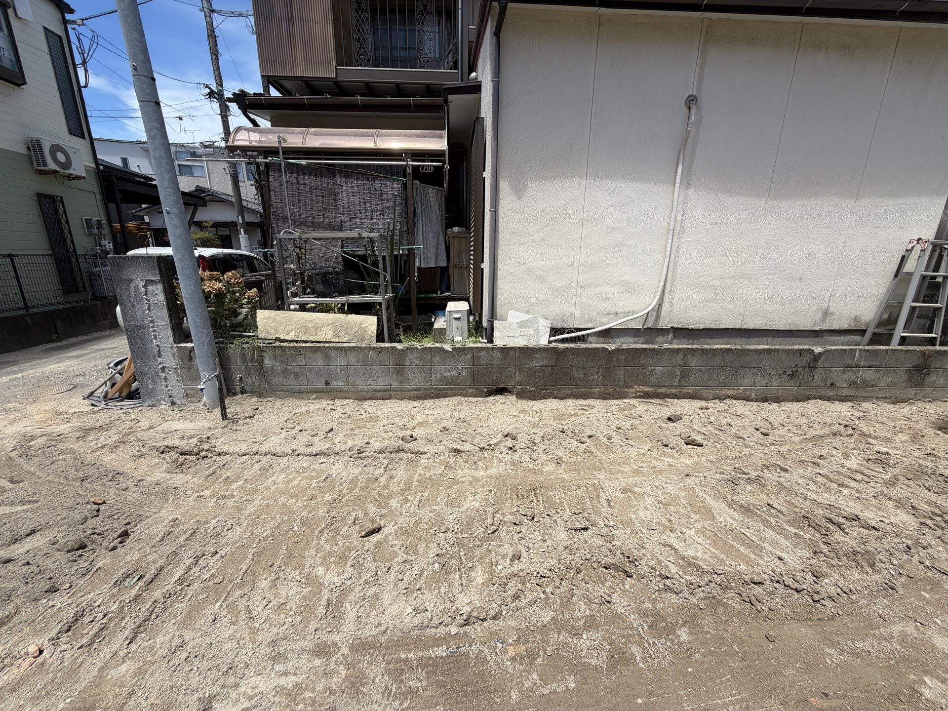 解体後の敷地とお隣の白い外壁。壁ぎわまで整地されている