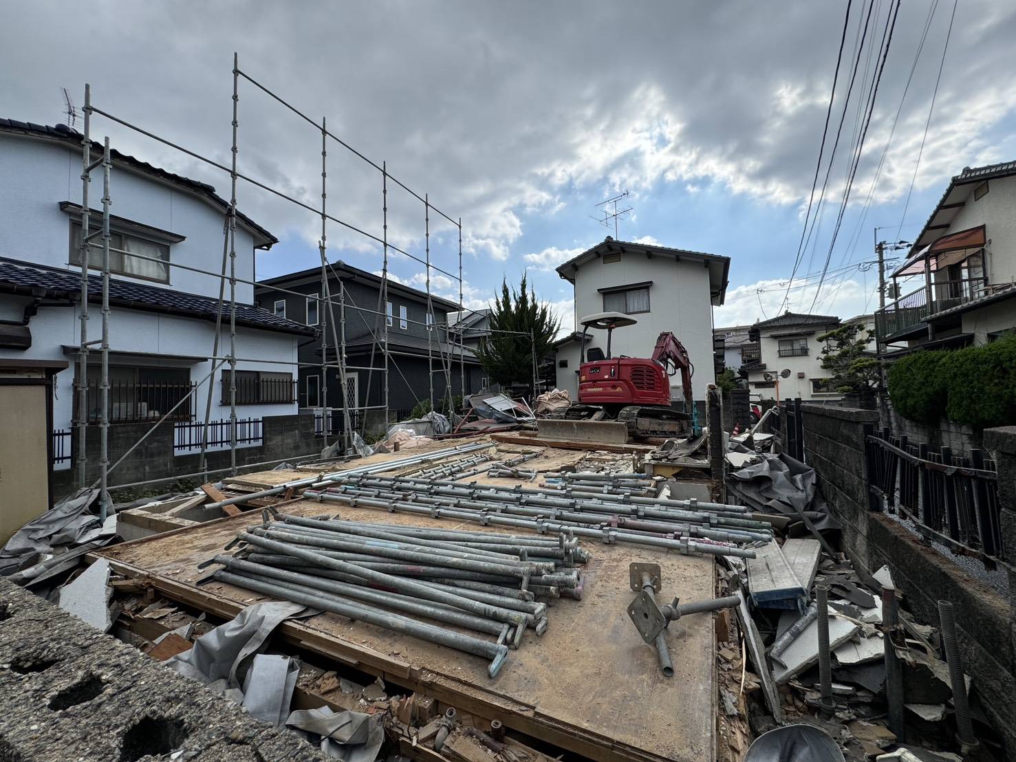 解体現場に残る足場と、地面に並べられた単管パイプ