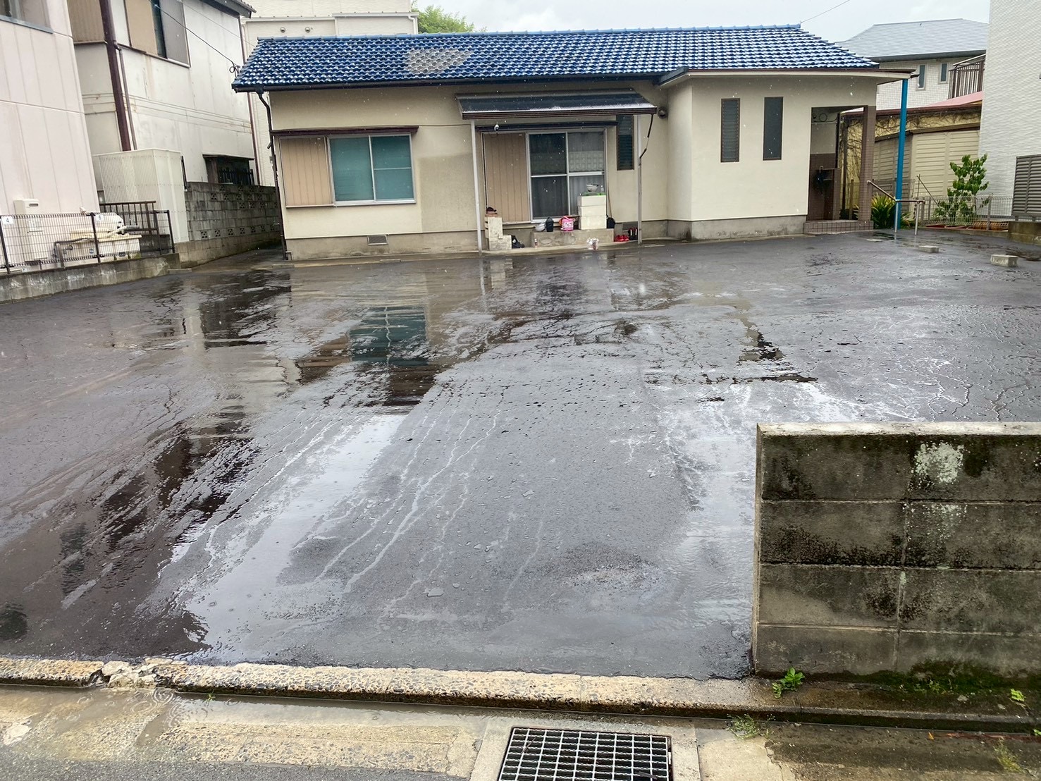 舗装された跡地とお隣の平屋住宅。境界のブロック塀が見える