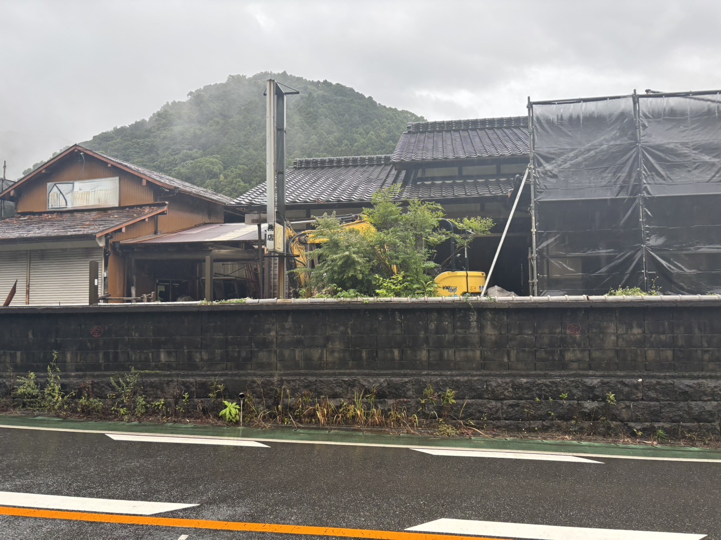 筑紫野市大石の解体現場。瓦屋根の木造の母屋と車庫が県道沿いに建つ