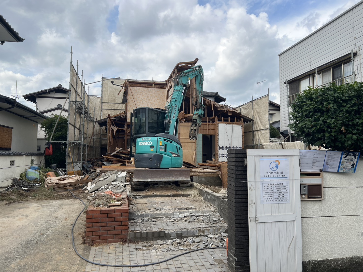 早良区有田の解体現場、門扉に掲示した建設業の許可票と重機
