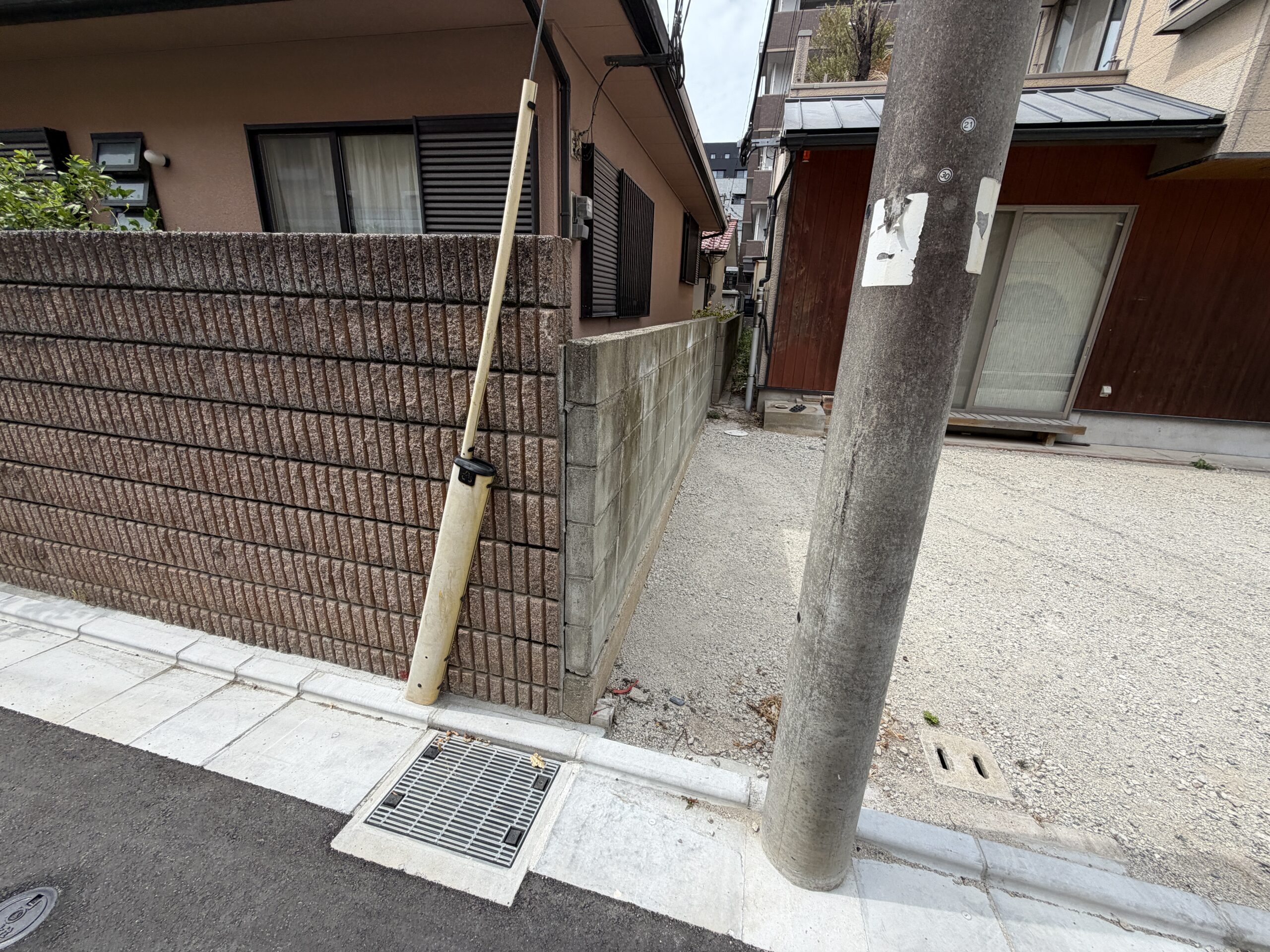 お住まいの側面とフェンス、砂利敷きの前庭の様子
