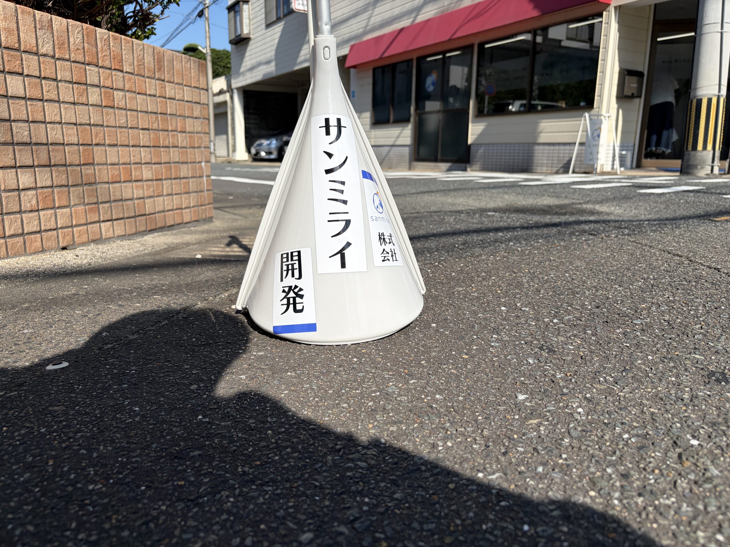 道路脇に立てられた、サンミライ開発の名前入りちりとり