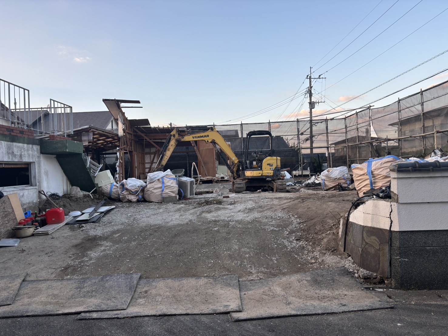 解体が進み、大きな袋が並ぶ野方の現場。奥で重機が作業している