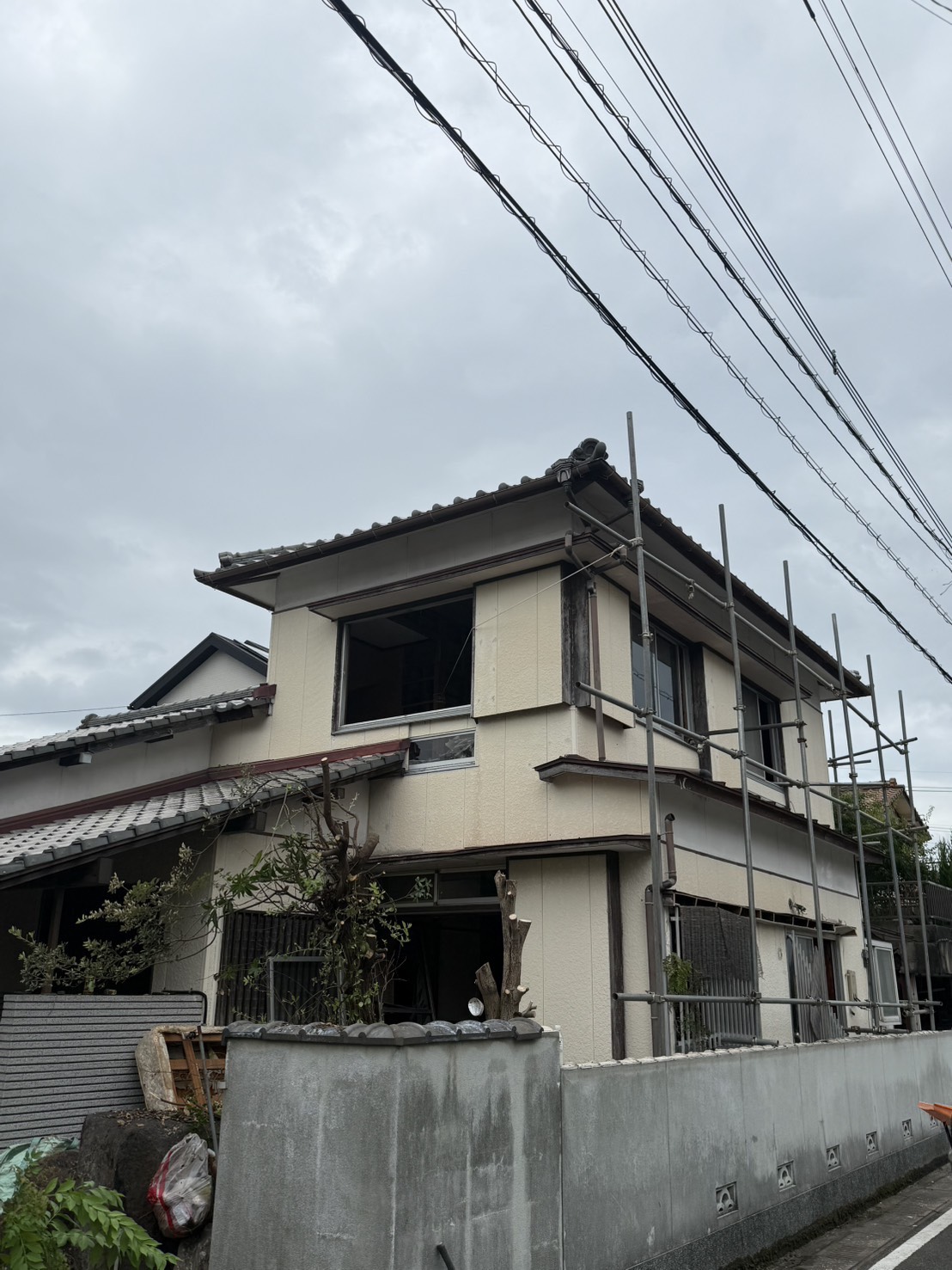 足場が組まれた、瓦屋根の木造2階建て住宅の外観