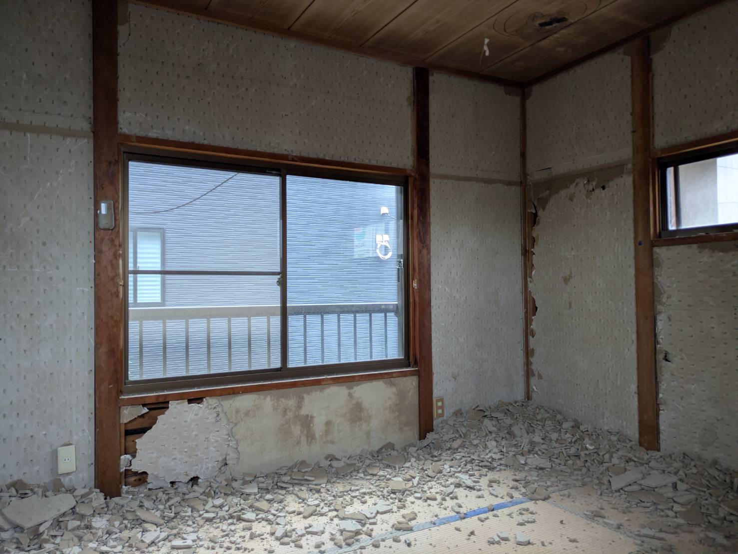 壁の仕上げがはがれ、床にかけらが積もった部屋