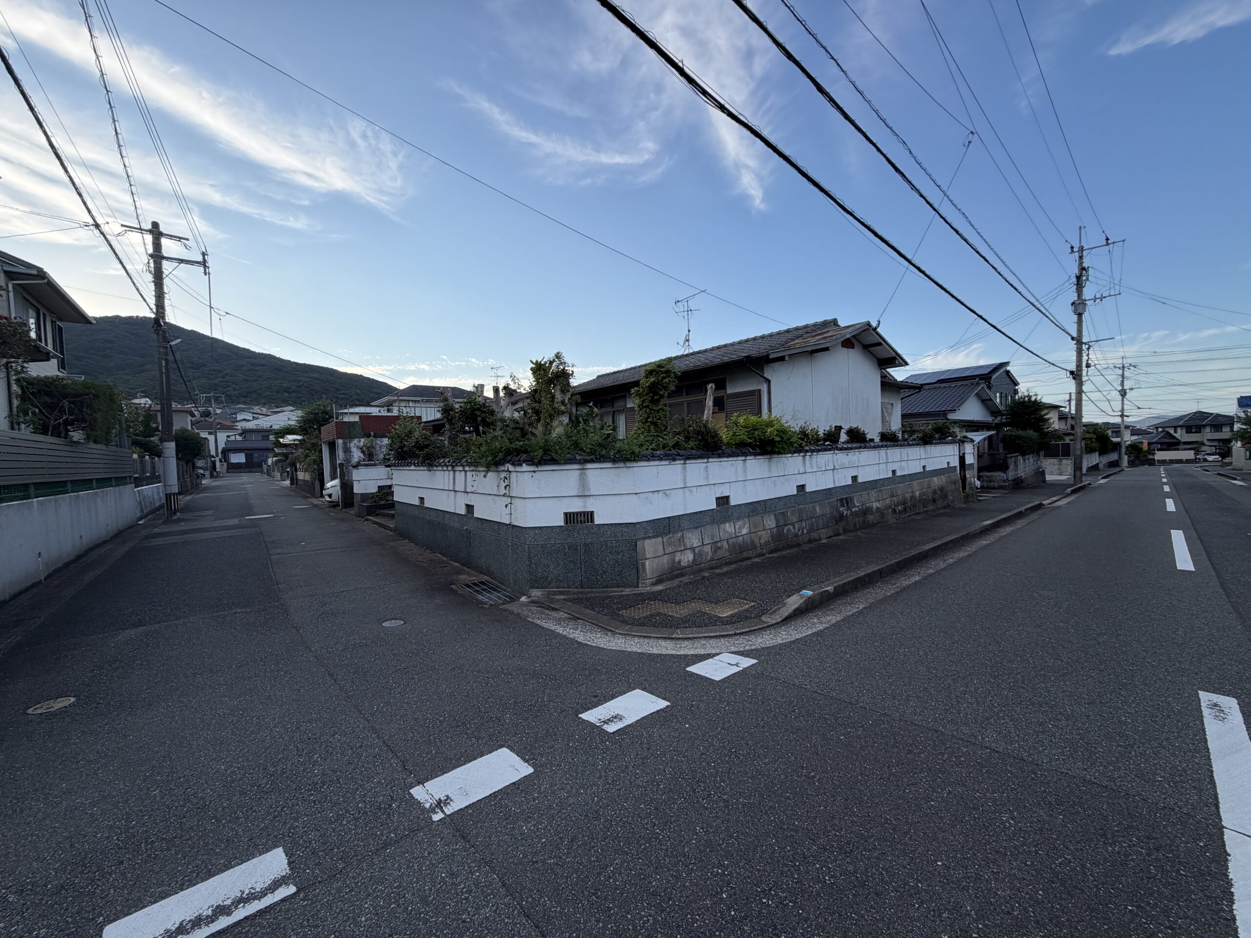 交差点の角から見た、白い塀が角に沿って曲がる敷地