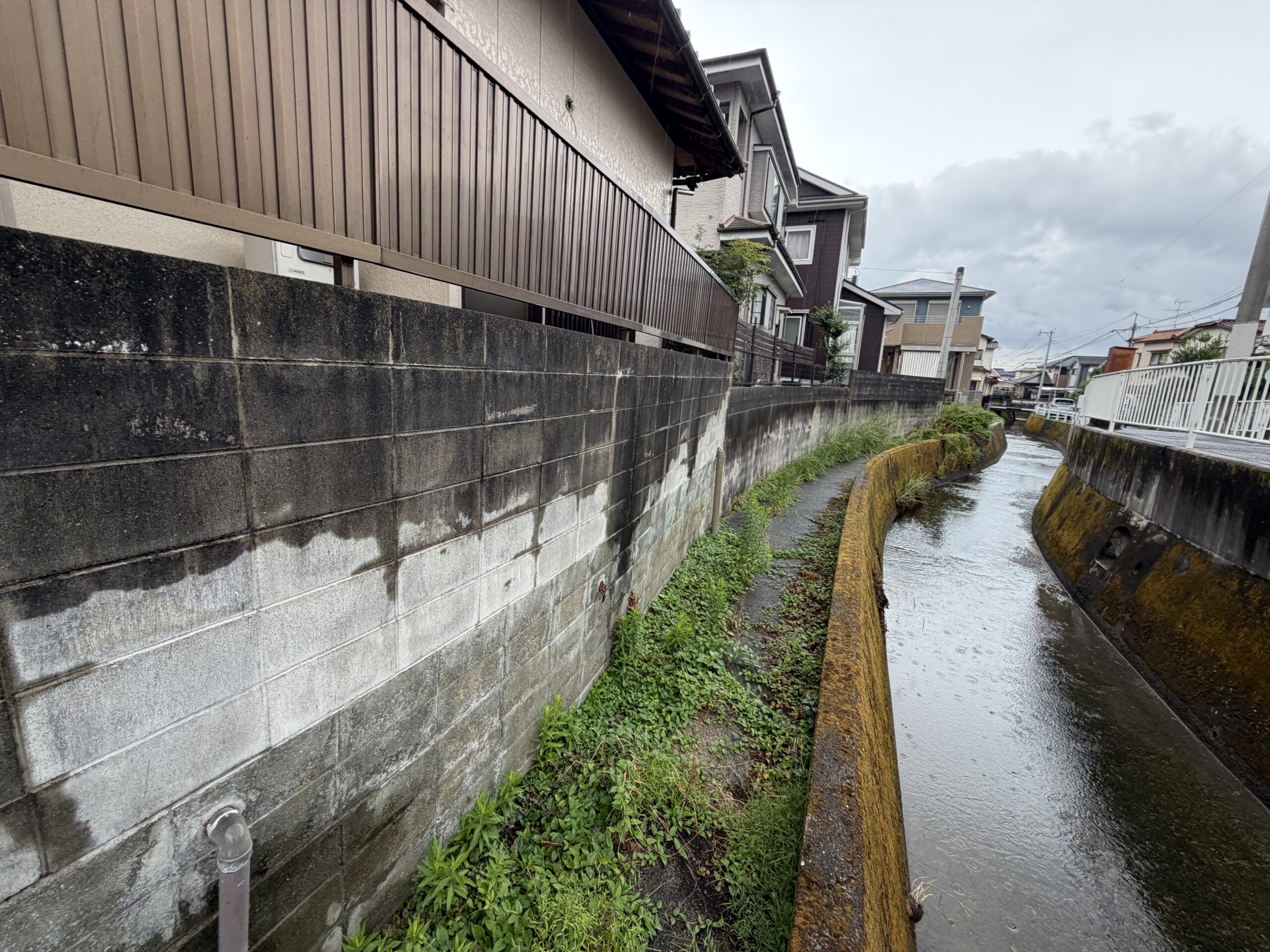 敷地の裏手を流れる水路と、敷地のブロック塀