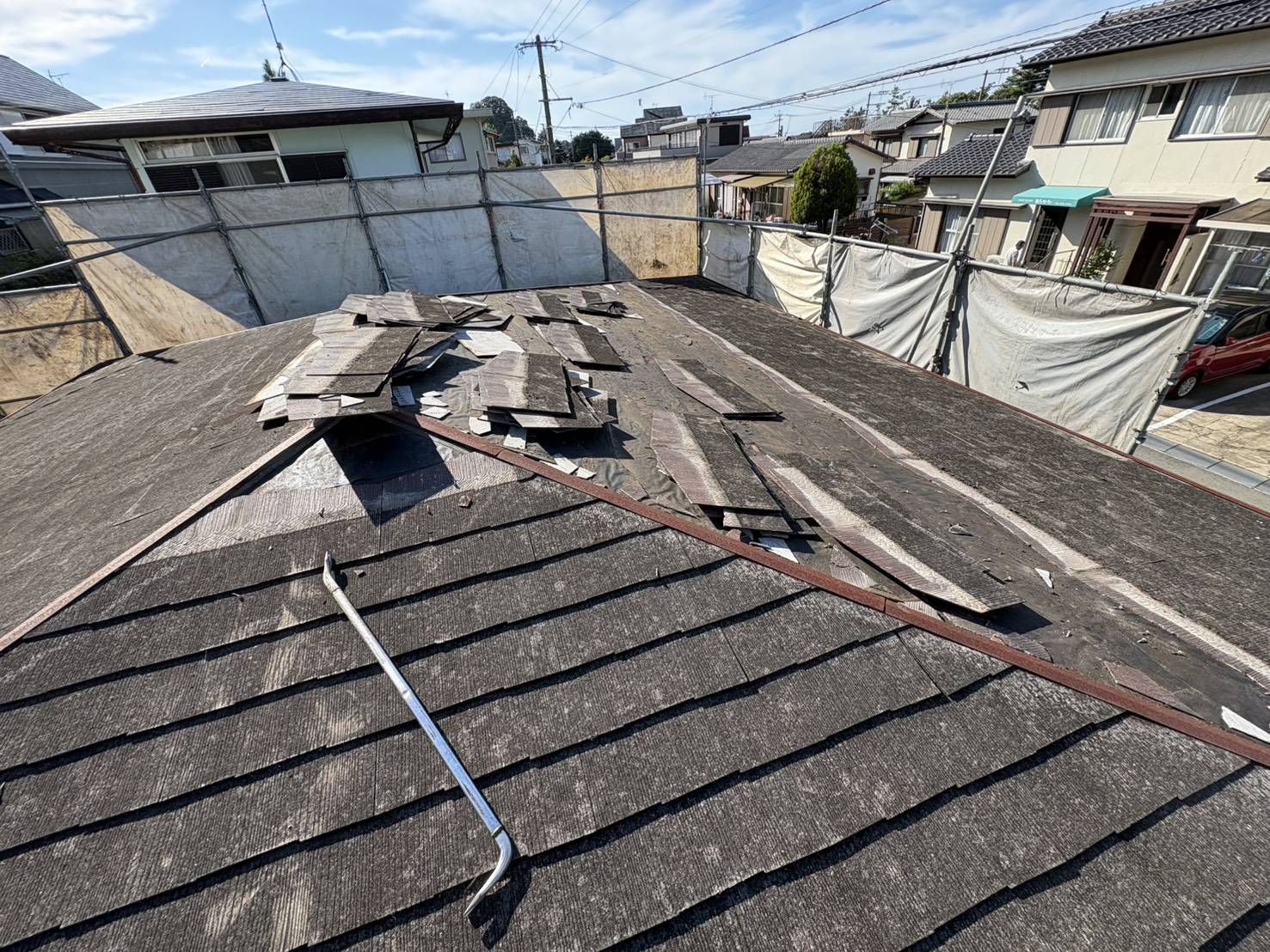 平屋の屋根の上で、屋根材を1枚ずつはがしている様子