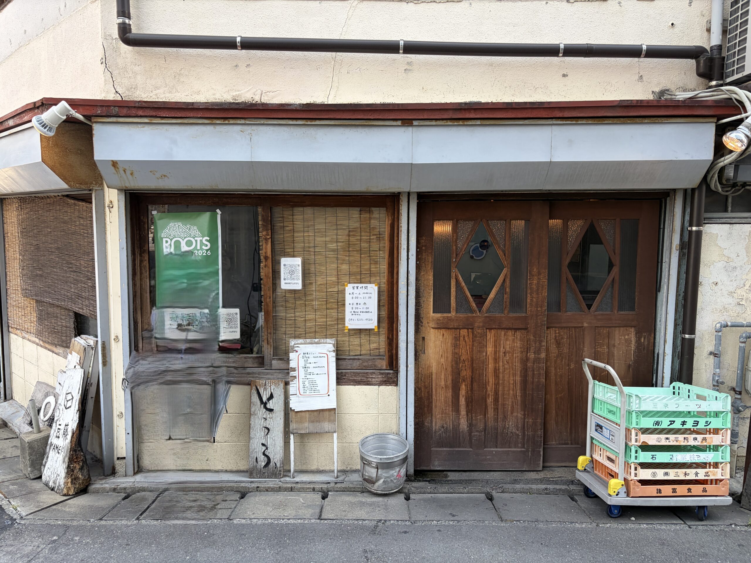 豆藤さんの1階の売り場。葦簀の下がった窓口と木の引き戸、店頭に貼られた案内