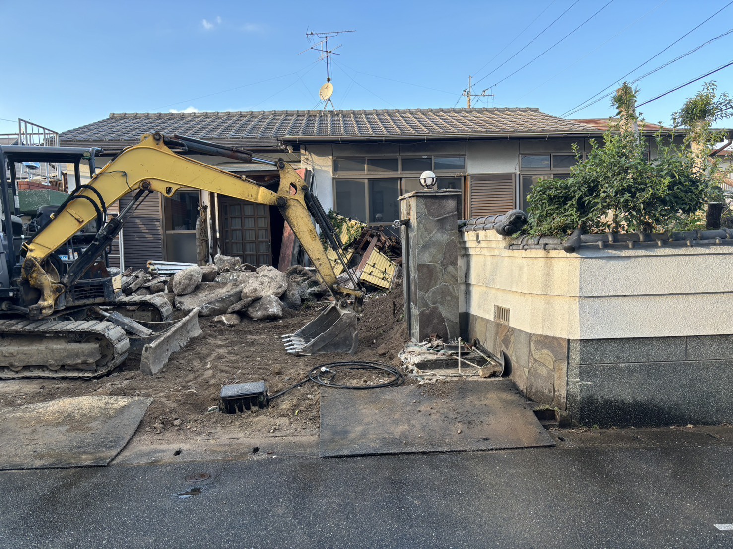 平屋の手前に入った重機。出入口の地面に鉄板が敷かれている