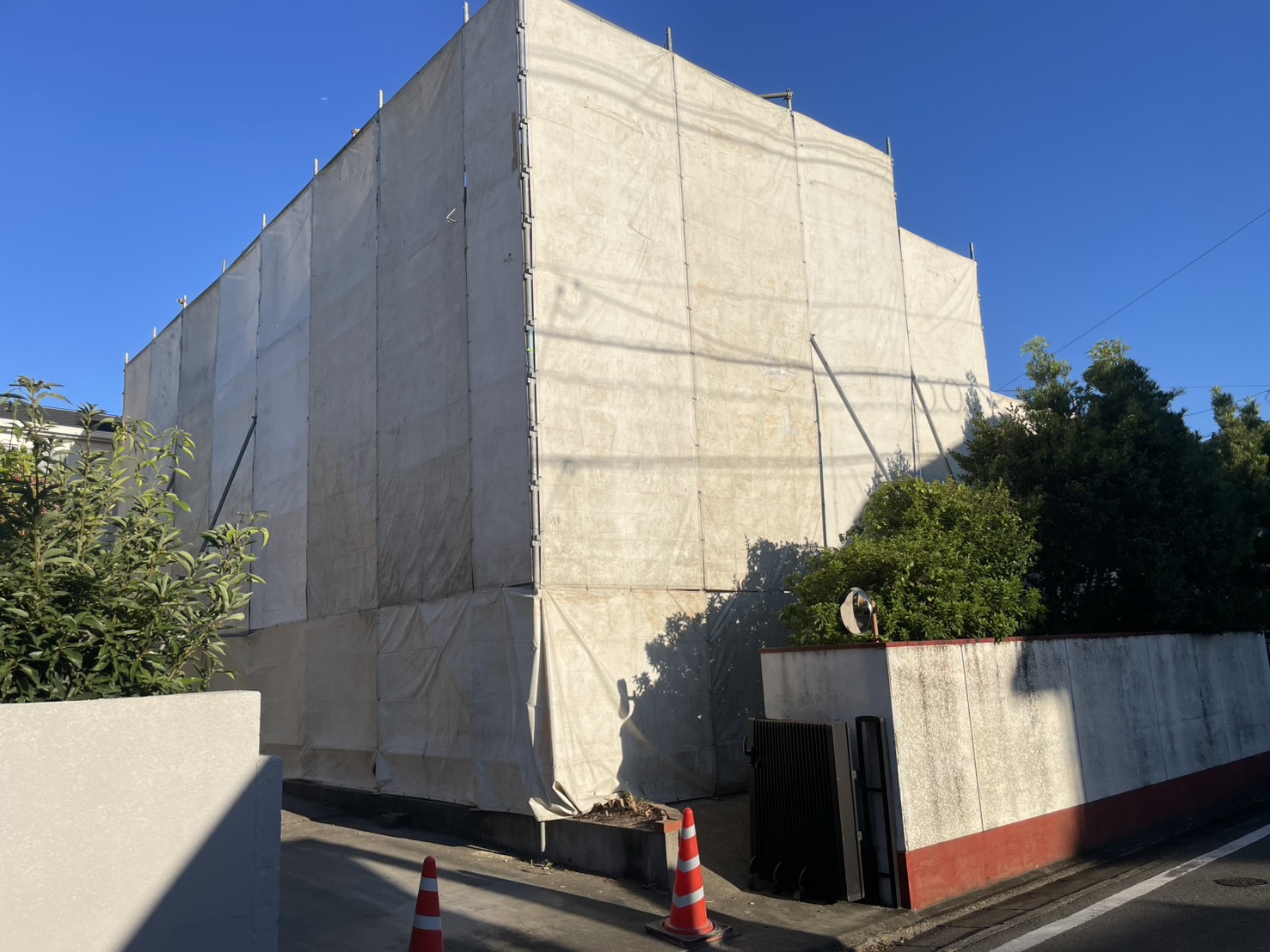 足場を組み、養生シートで覆った軽量鉄骨造の2階建て