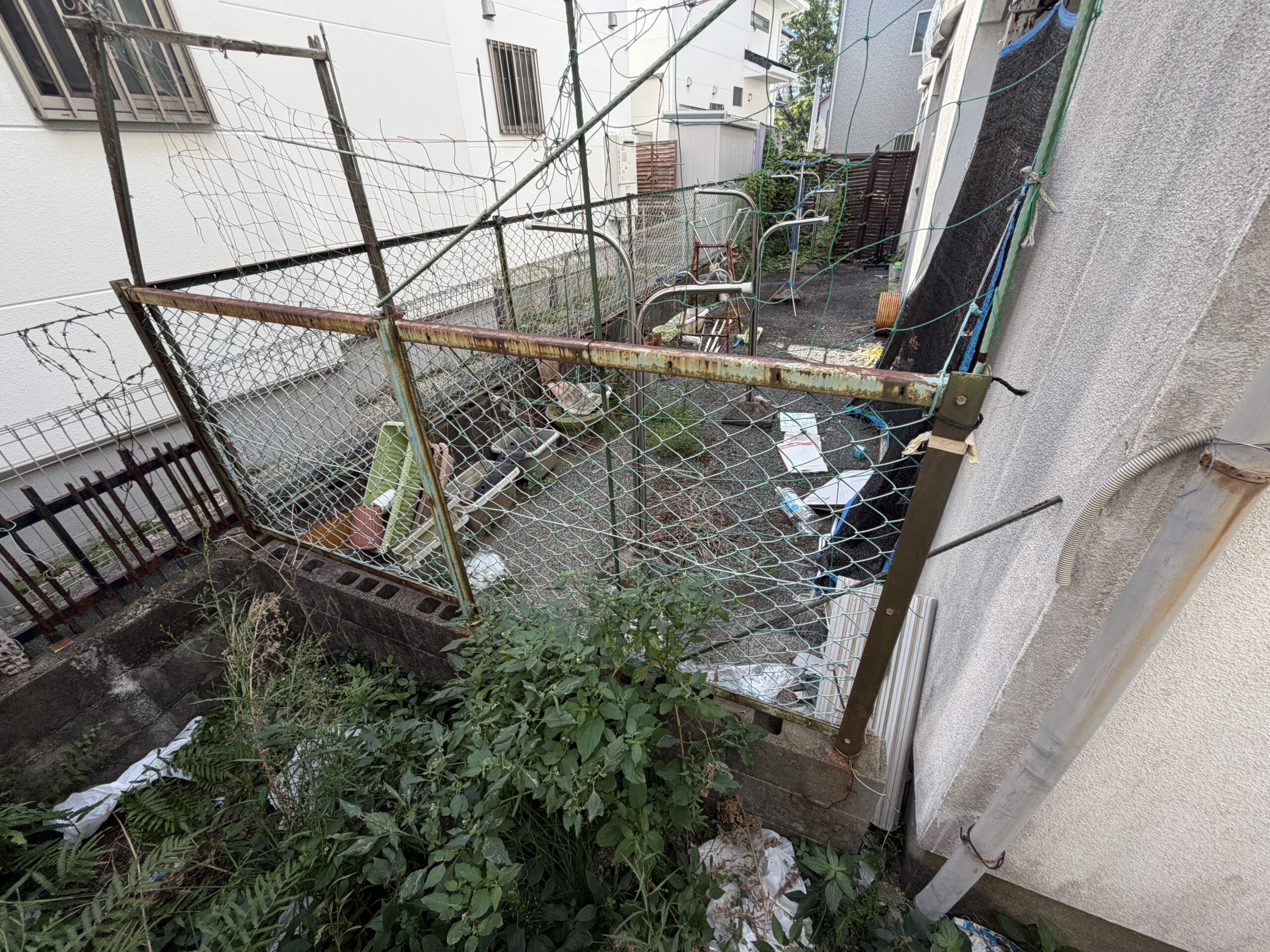 金網のフェンスごしに見た建物の裏手。プランターなどが置かれている