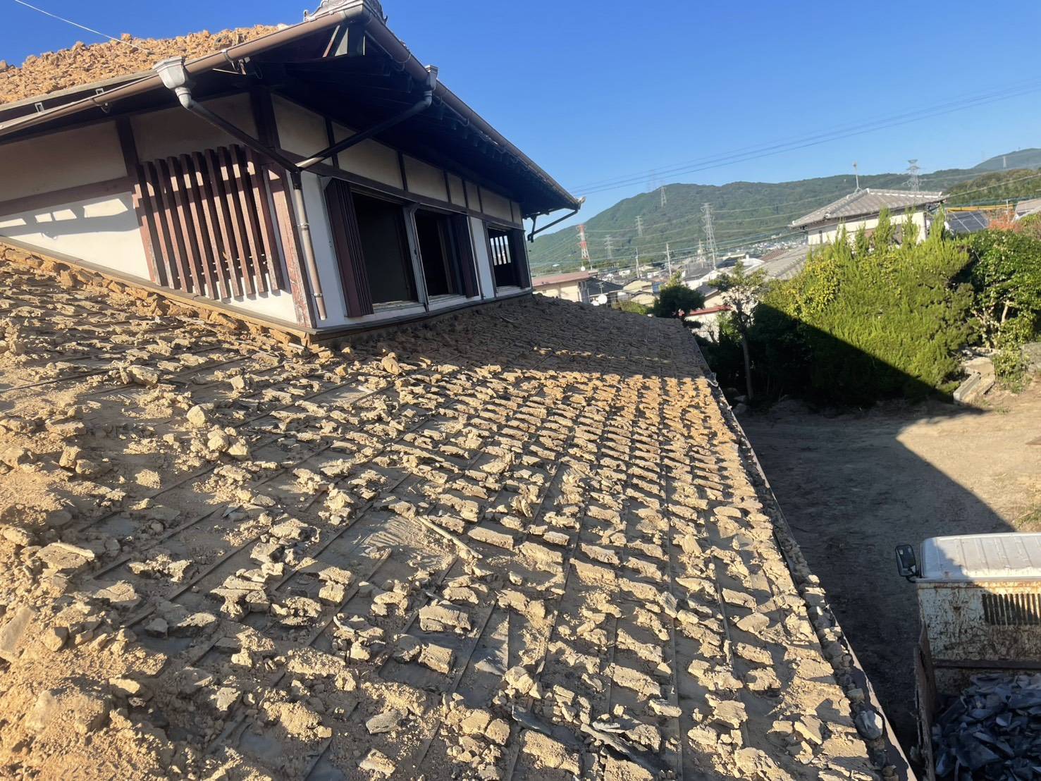 土が残る屋根と、その向こうに広がる山並み