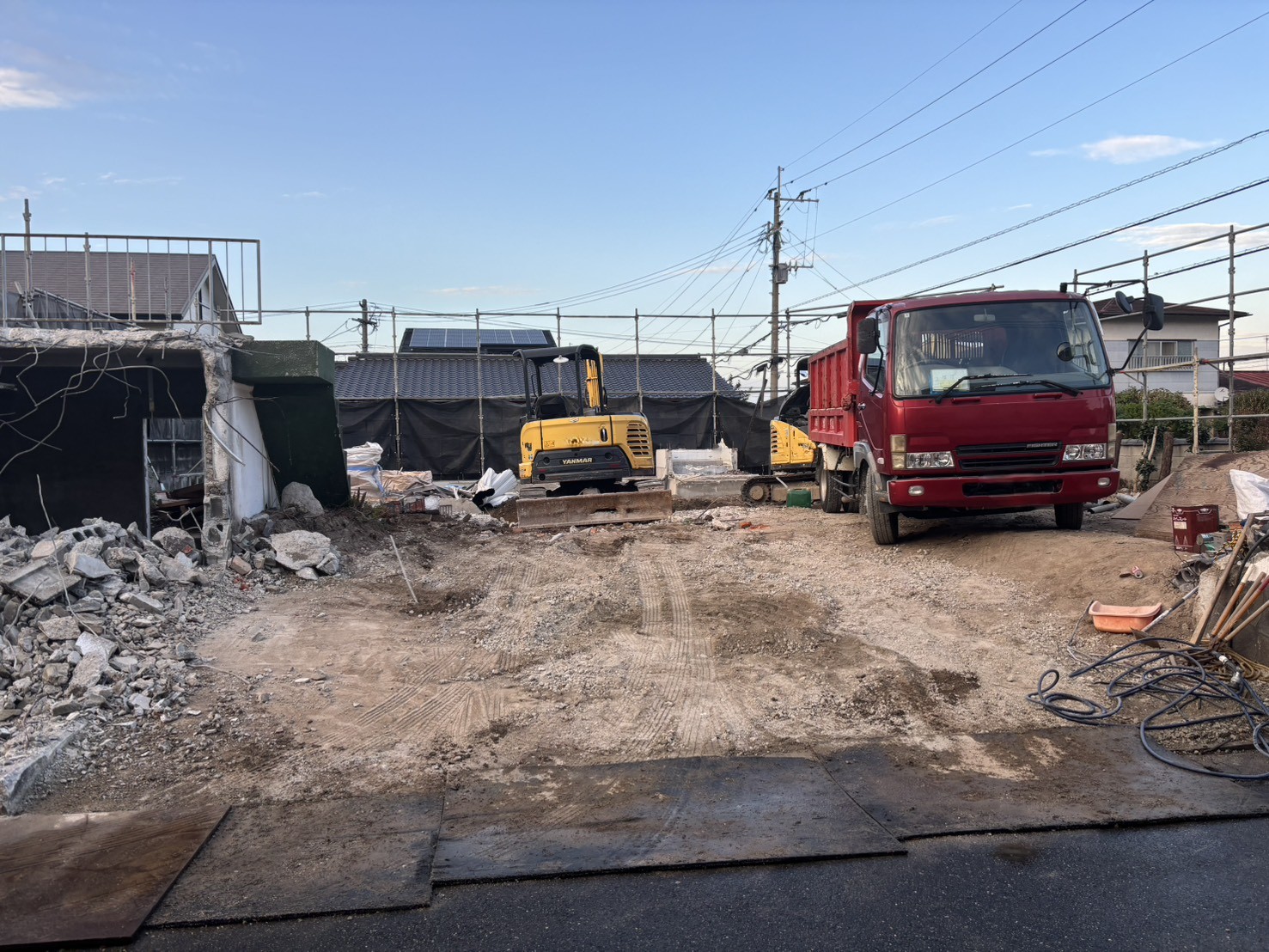 平屋のあった場所の地面が見えるようになった野方の現場と、重機とダンプ