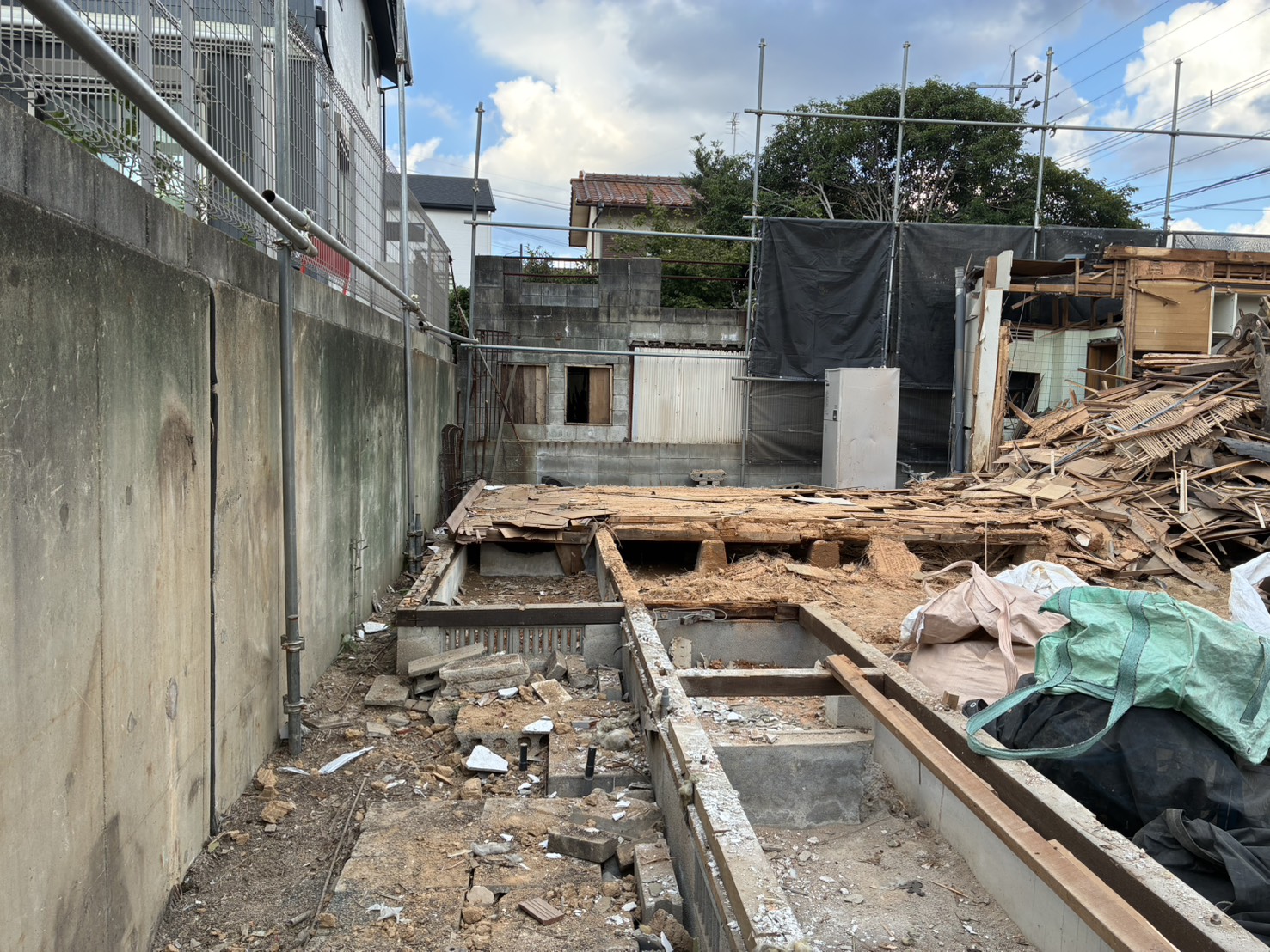 解体が進み、基礎が見えてきた現場と、寄せられた木材