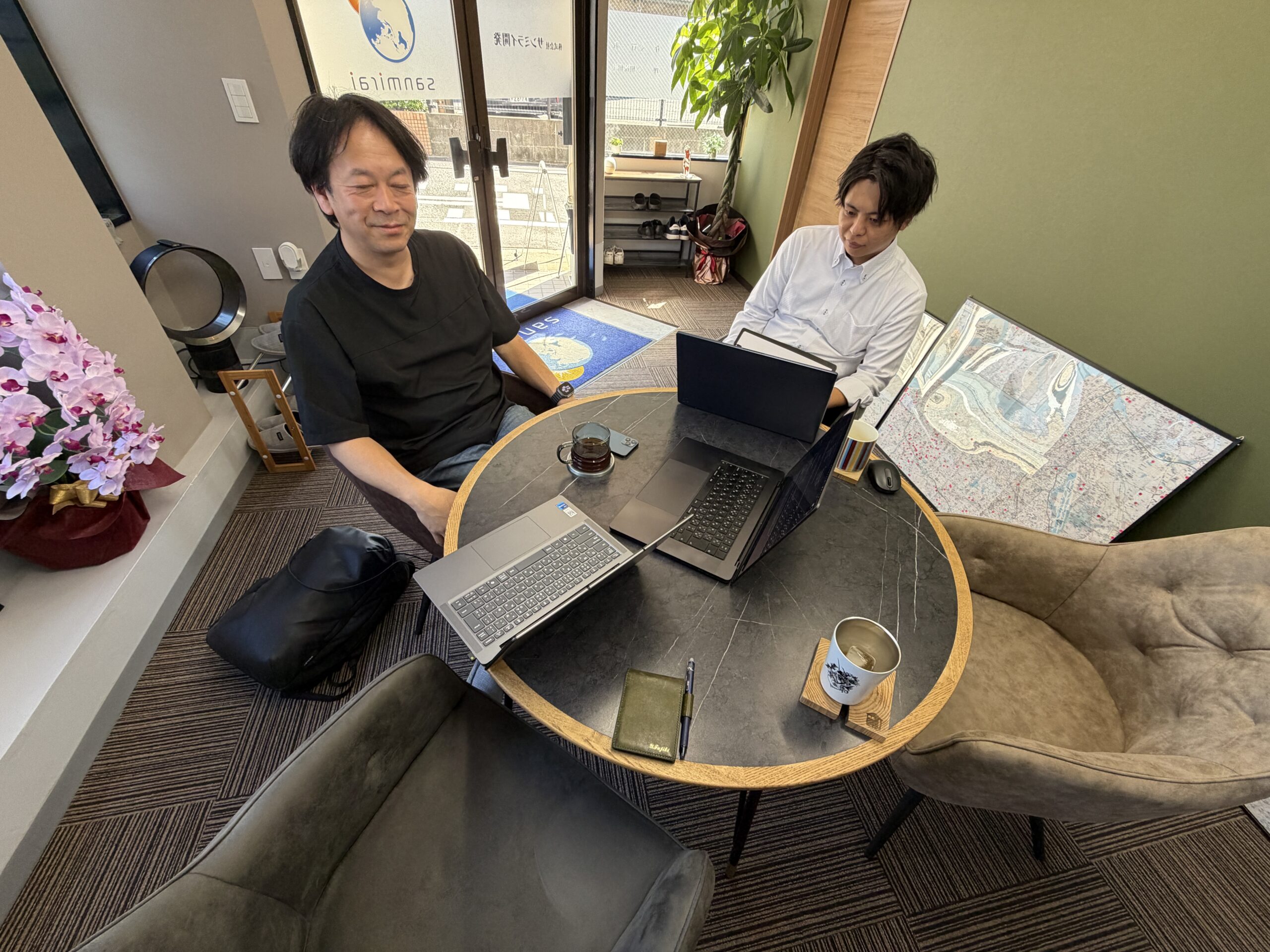 事務所の丸いテーブルを囲んで、アディザインの吉田さんにAIの使い方を教わる様子